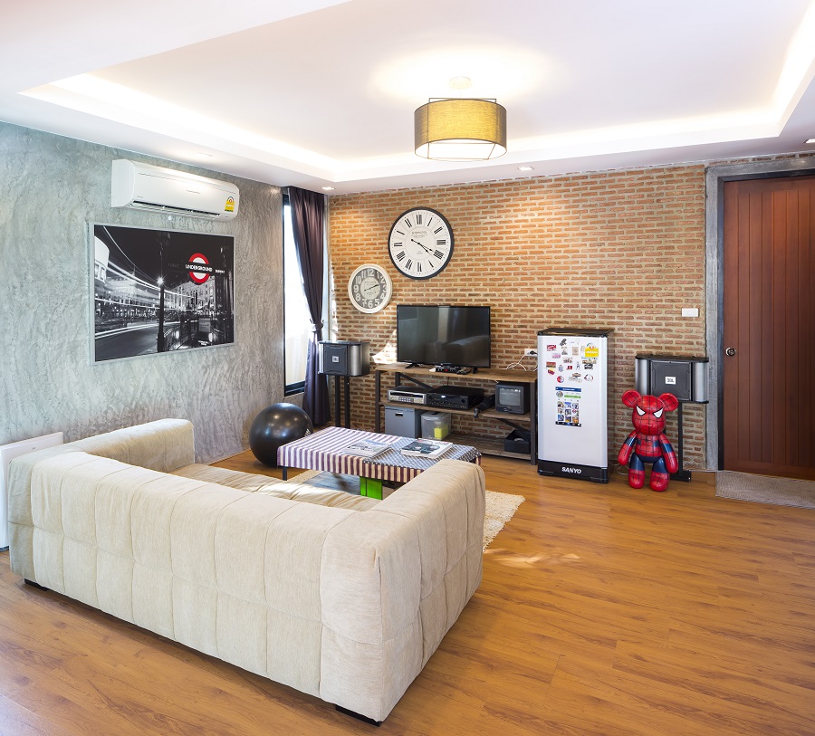 ห้องนั่งเล่นปูด้วยพื้นไม้ปาเก้ ผนังด้านซ้ายเป็นปูนเปลือยขัดมัน ที่ดู contrast กับผนังอิฐก่อ แต่ก็ให้ภาพรวมออกมาดูน่าสนใจ แสงและบรรยากาศออกมาให้ความรู้สึกอบอุ่นและผ่อนคลาย