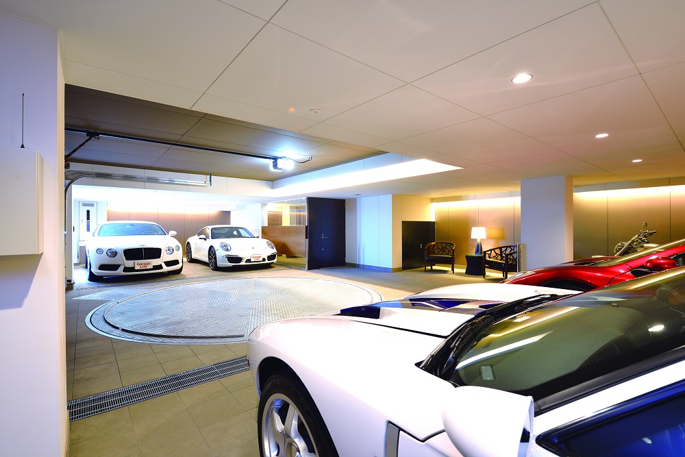 โรงจอดรถที่ซูเปอร์สปอร์ตคาร์จอดพัก มีพื้นที่กว้าง บรรยากาศงดงาม ตกแต่งด้วยของที่ใช้วัสดุต่างชนิดกันแต่คุมด้วยโทนสีเดียวกันคือขาวและน้ำตาล ทำให้ดูหมือนเลานจ์ในโรงแรมที่ดูสบาย ๆ ตามแบบที่คุณ T คิด