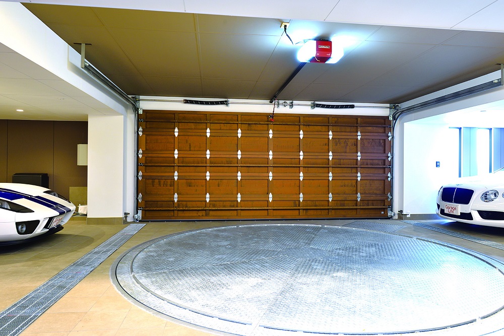 คุณ T บอกว่า “เน้นประตูที่เปิดปิดได้รวดเร็ว เพราะอยู่ริมถนนที่มีรถมาก” เขาจึงเลือก “World Garage Door” แบบไม้ และใช้อุปกรณ์เปิดปิดประตูของ “Lift Master”