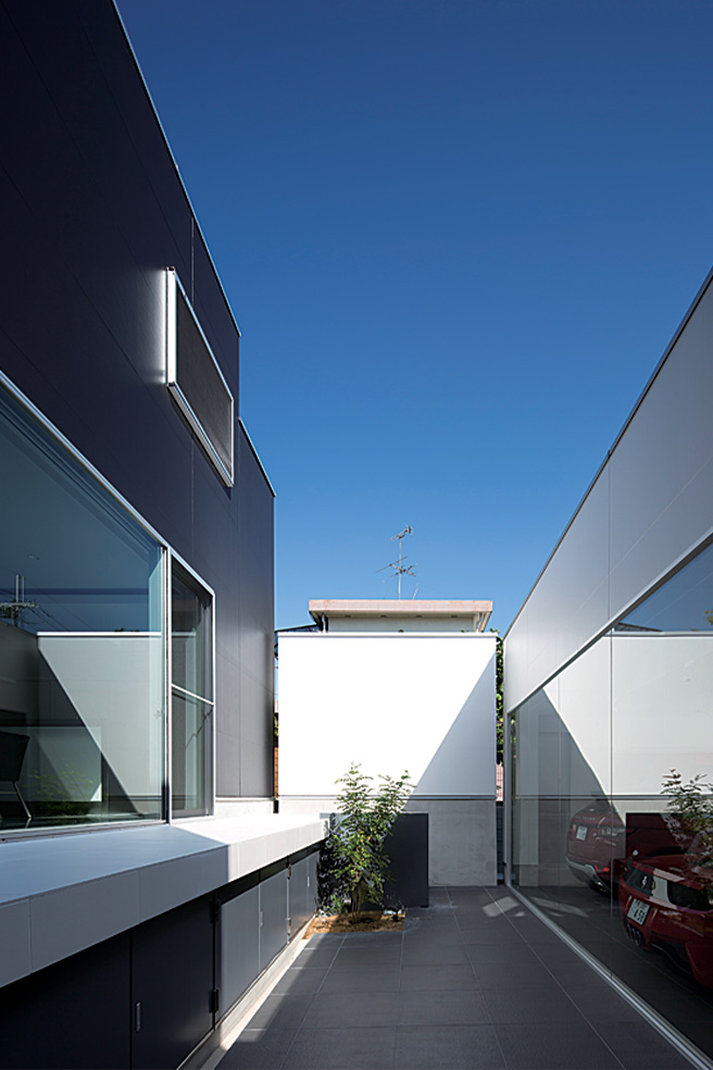 พื้นที่ว่างทำเป็นสวนอยู่ระหว่างโรงจอดรถและตัวบ้าน ทำให้รู้สึกปลอดโปร่งโล่งสบาย โดยไม่ต้องกังวลกับสายตาจากภายนอก มีการคำนวณระยะระหว่างห้องนั่งเล่นกับโรงจอดรถไว้อย่างดี ทำให้รถกลายเป็นส่วนหนึ่งของบ้านอย่างเป็นธรรมชาติ