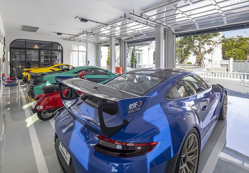 ประตูโรงจอดรถแบบ Overdoor ของ Kongo Door นำเข้าจากประเทศญี่ปุ่น ดีไซน์สวยงาม การเปิด-ปิด แบบขึ้น-ลง ทำให้ประหยัดพื้นที่ ภายในโรงจอดรถ MR.Lee ต้องการความสว่างจึงทาสีขาว ทำให้รถที่จอดดูโดดเด่น แม้เวลาปิดประตูโรงจอดรถมองทะลุเข้าไปรถที่จอดอยู่ข้างในก็ยังเด่นมาก