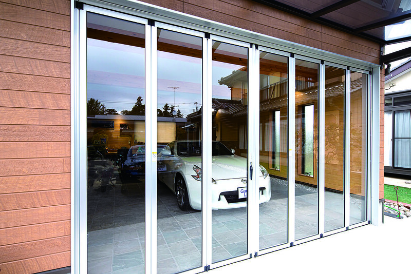 ใช้ประตูบานเฟี้ยมเป็นประตูโรงจอดรถ นอกจากจะดูรถจากอาคารหลักได้ตลอดเวลาแล้ว แสงไฟยังช่วยให้มีบรรยากาศเหมือนโชว์รูม