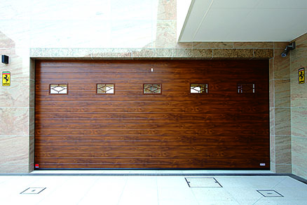 ประตูโรงจอดรถ ซึ่งเป็นหน้าตาของโรงจอดรถ ใช้ประตูชัตเตอร์ EUGA ของ “Sanwa Shutter” ประตูลายไม้ที่ดูขรึมเข้ากับผนังหิน ทำให้ดูเป็น“ห้องงานอดิเรกของผู้ใหญ่” ส่วนประตู Maintenance Garage ซึ่งสูง ใช้ประตูชัตเตอร์แบบม้วนขึ้น